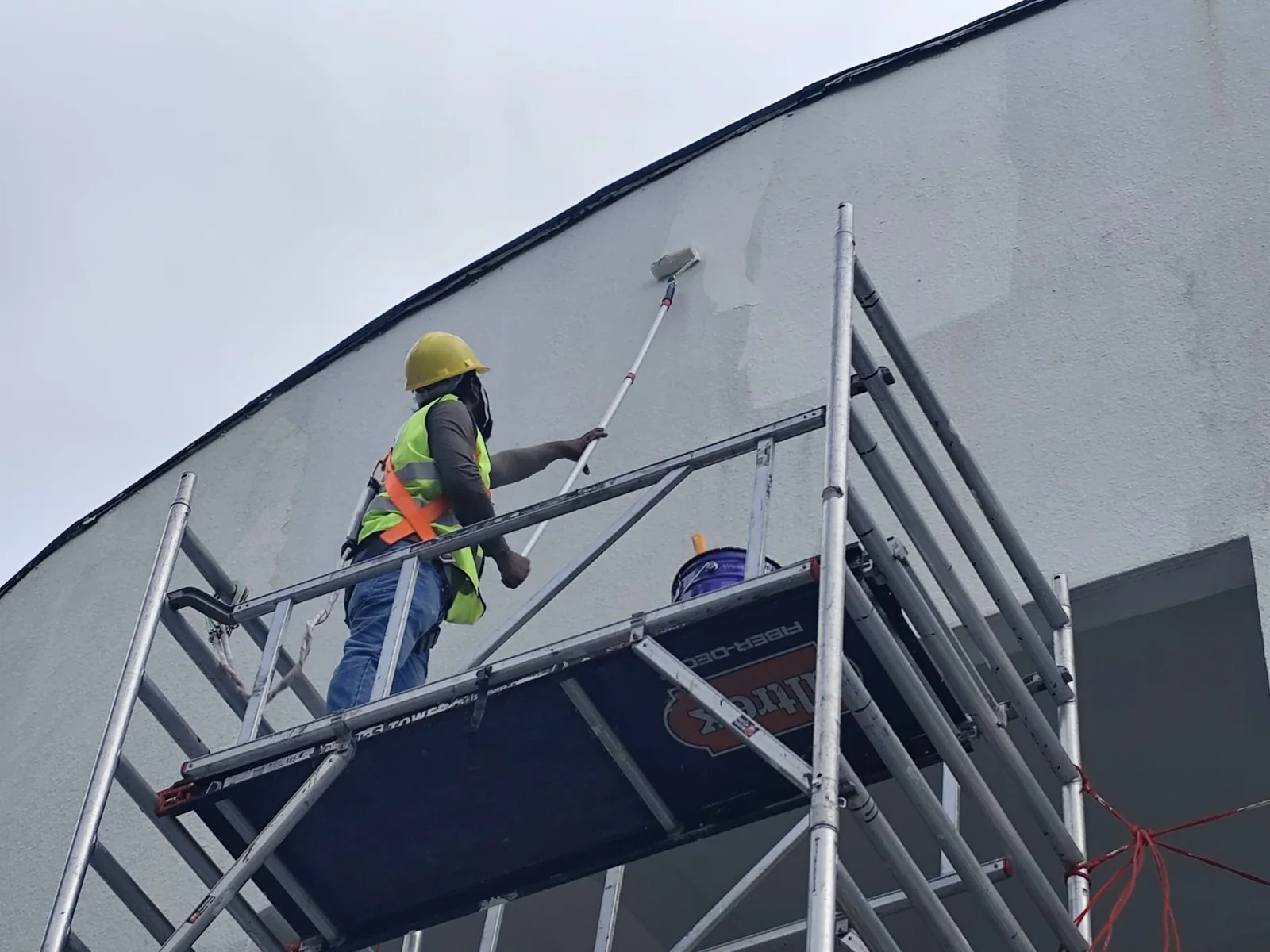 Technician working from a scaffold beside a building exterior